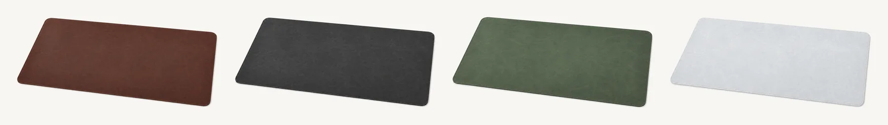 Les quatre coloris du sous-main Maroquine alignés sur fond studio : marron brun foncé, noir charbon, vert kaki et gris clair